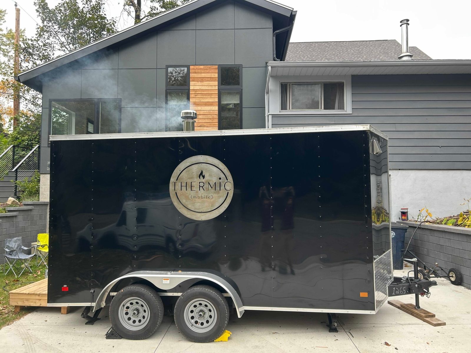 Side view of the Thermic trailer with woodsmoke rising from the chimney as the stove heats up.